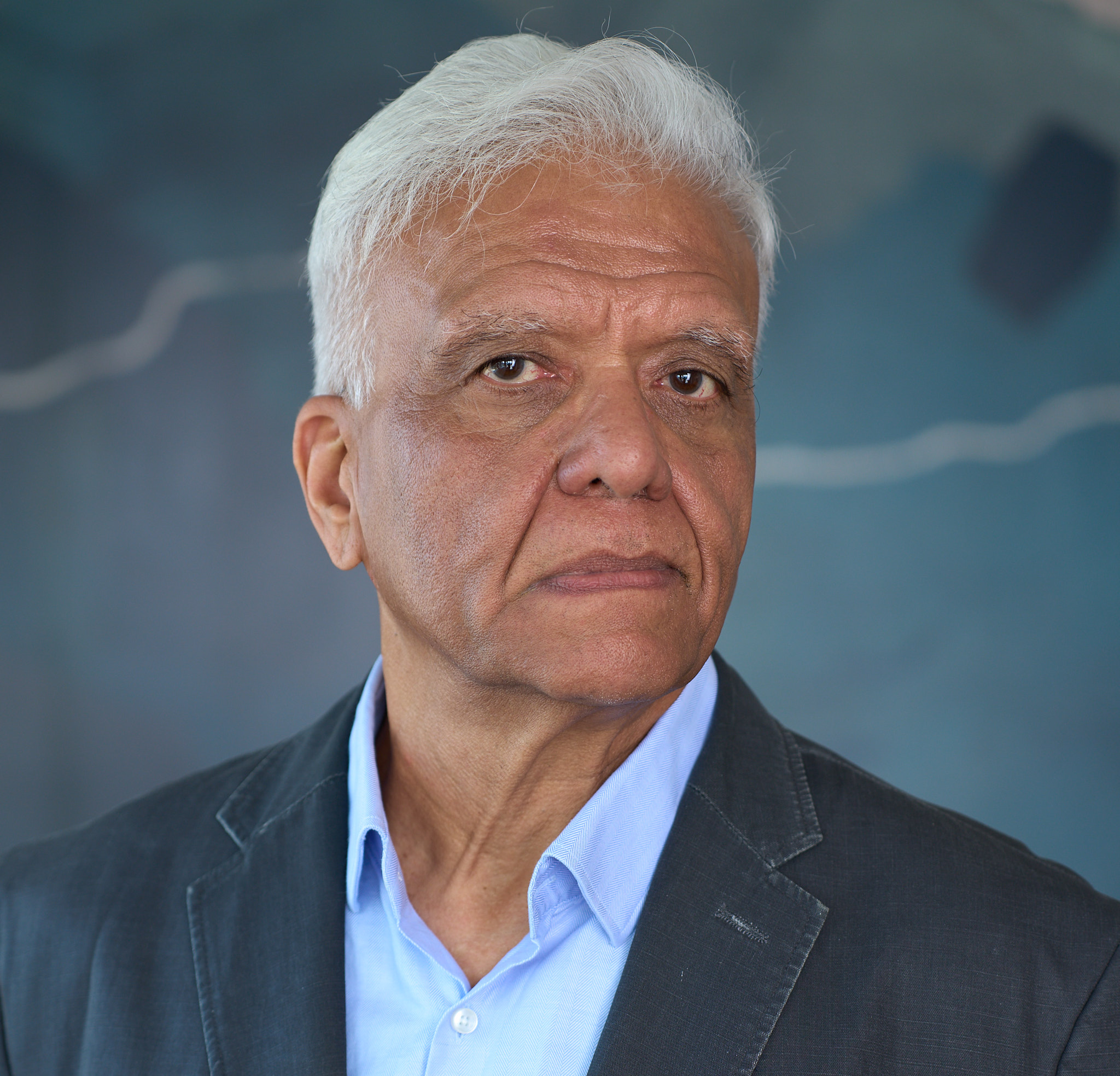 Upinder Raisauda in a serious close headshot wearing a dark jacket and blue shirt
